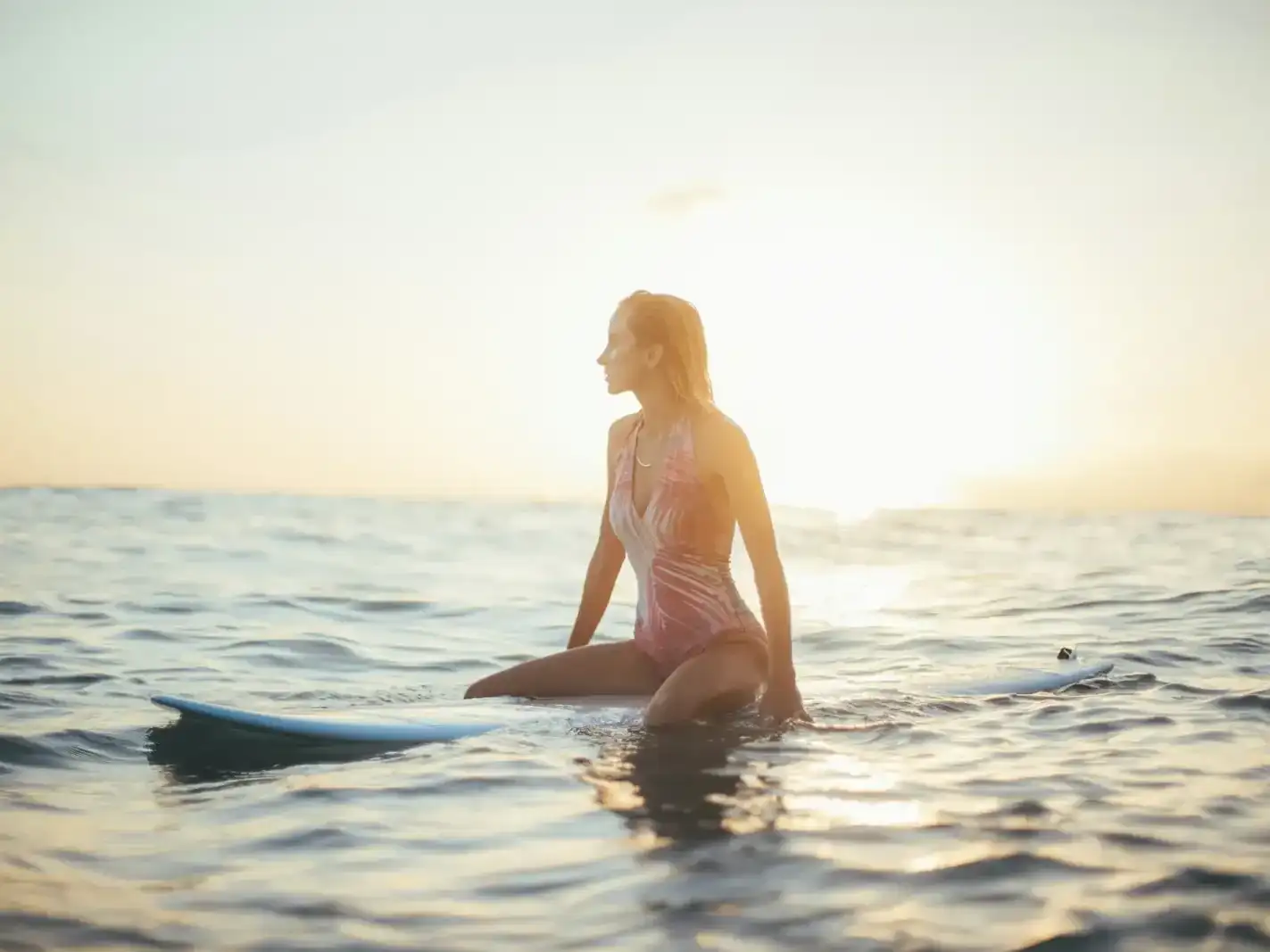 A swimmer standing in calm sea water at sunrise