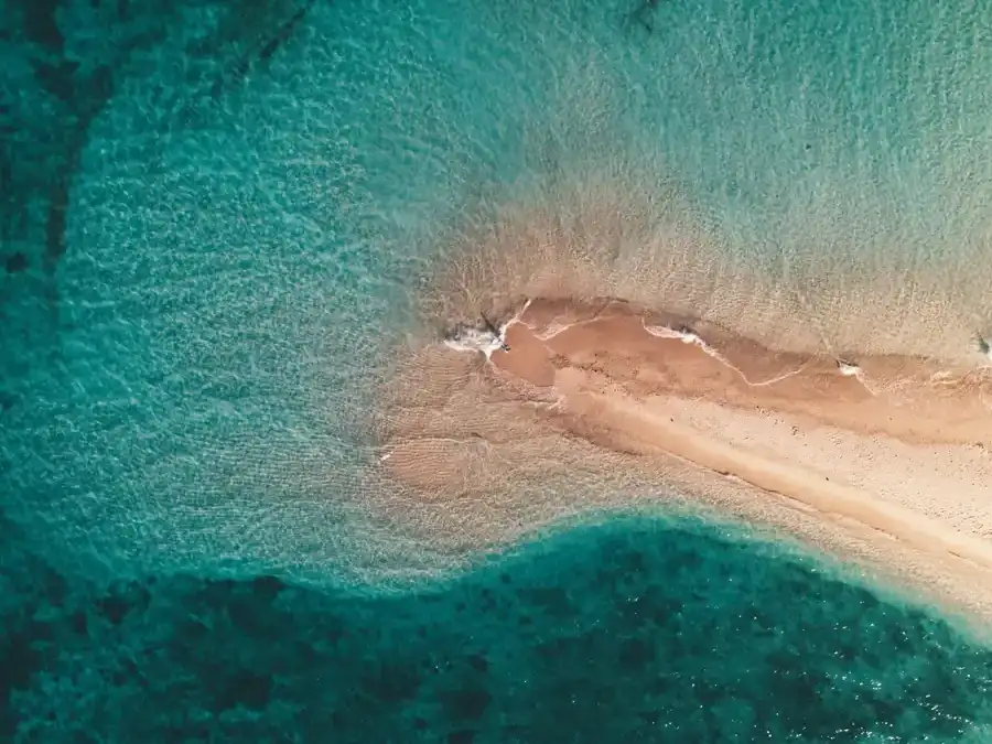 A small sandy island ringed by turquoise water, seen from above